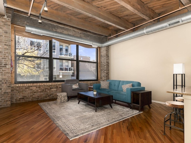 living room with hardwood / wood-style floors, track lighting, beam ceiling, wood ceiling, and brick wall