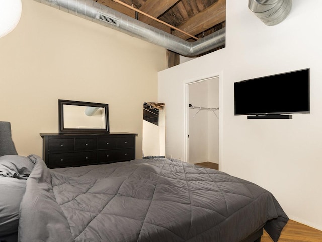 bedroom with a spacious closet, a closet, and wood-type flooring