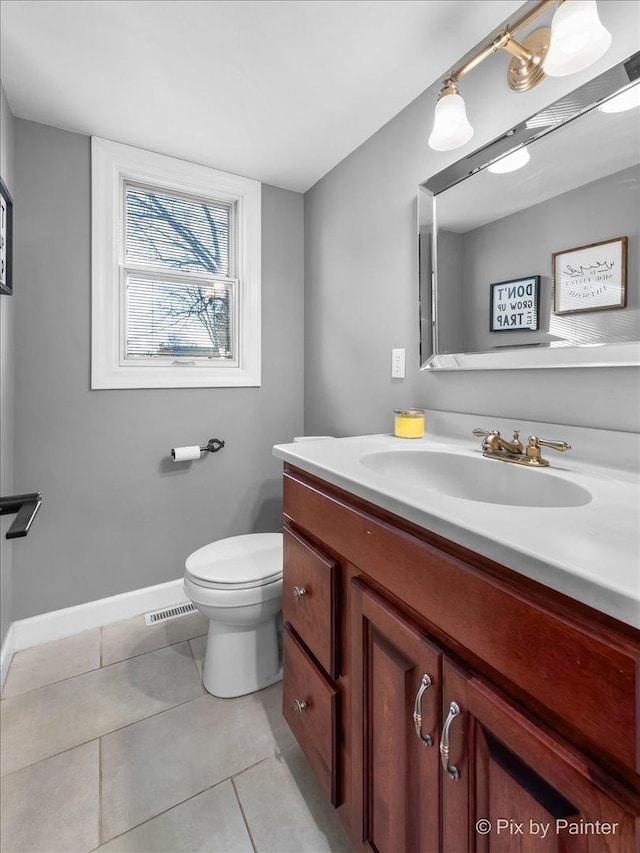 bathroom with toilet, vanity, and tile patterned floors