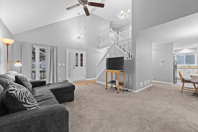 living room featuring sink, ceiling fan with notable chandelier, high vaulted ceiling, and carpet