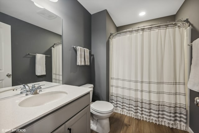 bathroom with hardwood / wood-style floors, vanity, toilet, and walk in shower