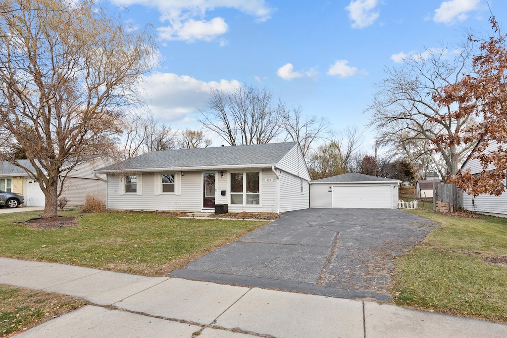 ranch-style home featuring a garage, an outbuilding, and a front lawn