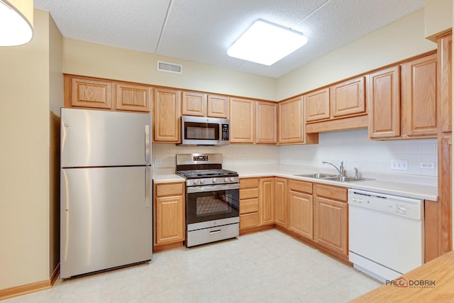 kitchen featuring sink, backsplash, a textured ceiling, light brown cabinetry, and appliances with stainless steel finishes