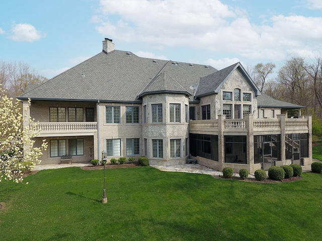 rear view of house featuring a yard and a balcony