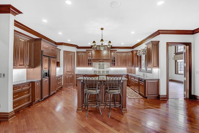 kitchen featuring a center island, sink, paneled fridge, light stone counters, and decorative backsplash