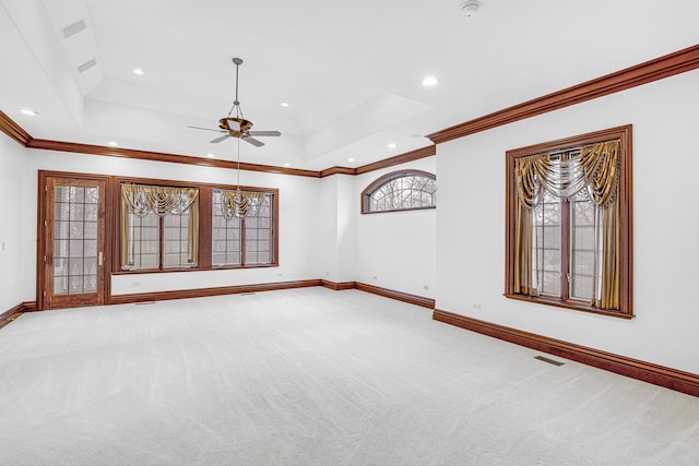 spare room featuring a raised ceiling, ceiling fan, crown molding, and light carpet