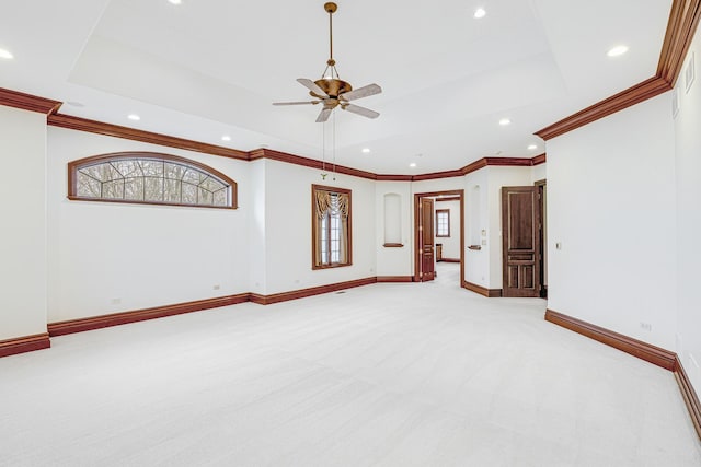 empty room with light colored carpet, a raised ceiling, ceiling fan, and ornamental molding