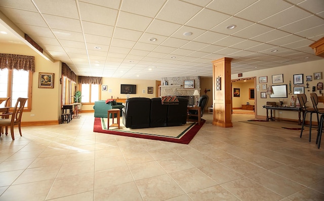 tiled living room with decorative columns and a drop ceiling