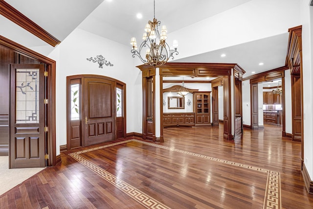 entryway with hardwood / wood-style floors, a notable chandelier, ornamental molding, and high vaulted ceiling