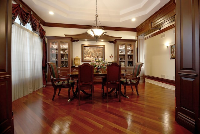 dining space with a tray ceiling, dark hardwood / wood-style floors, and ornamental molding