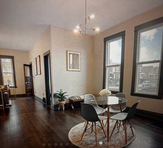 dining space featuring dark hardwood / wood-style flooring, an inviting chandelier, and vaulted ceiling