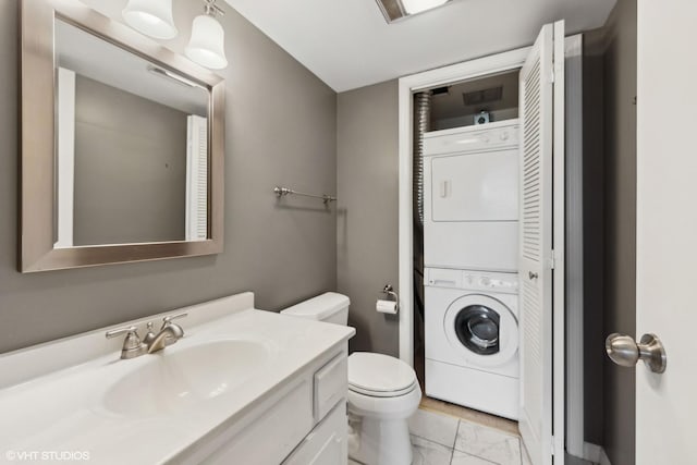 bathroom featuring stacked washer / dryer, toilet, and vanity