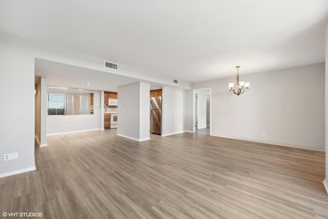 unfurnished living room featuring a chandelier and light hardwood / wood-style floors