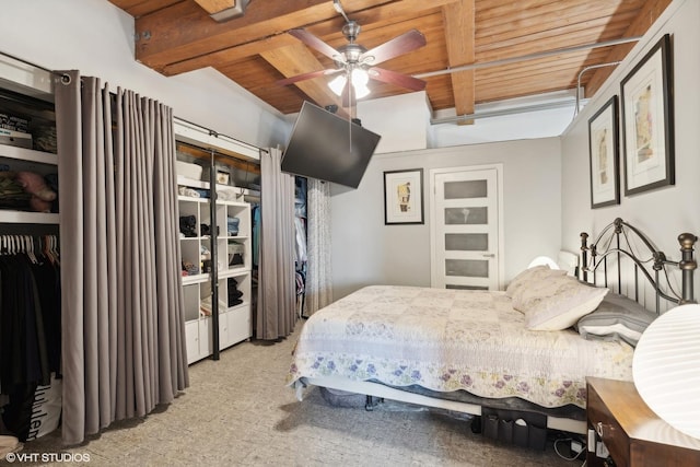 bedroom with beam ceiling, ceiling fan, a closet, and wooden ceiling