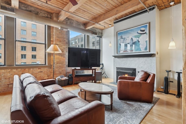 living room featuring beam ceiling, light wood-type flooring, brick wall, and wooden ceiling