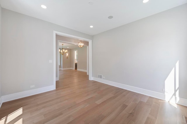 spare room featuring an inviting chandelier and light hardwood / wood-style flooring