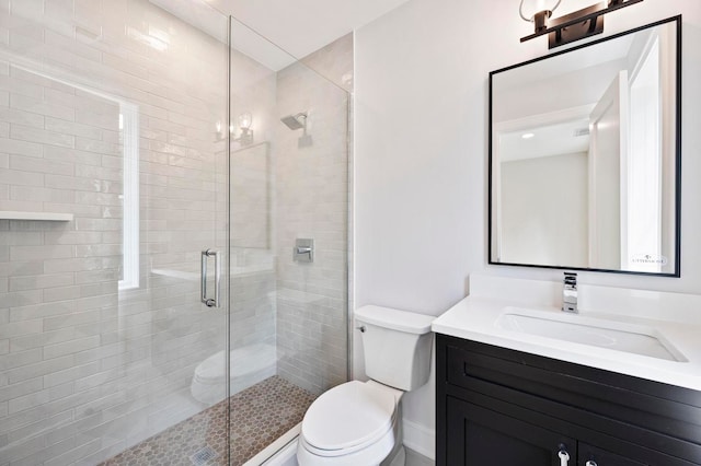 bathroom featuring vanity, toilet, and a shower with shower door