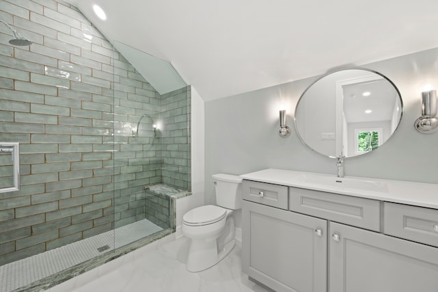 bathroom with vanity, toilet, a tile shower, and vaulted ceiling