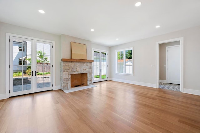 unfurnished living room featuring light hardwood / wood-style flooring and a stone fireplace