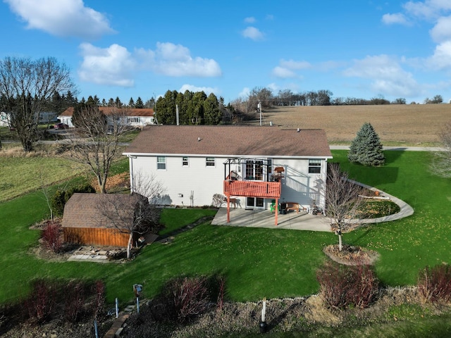 rear view of property with a lawn, a rural view, a deck, and a patio