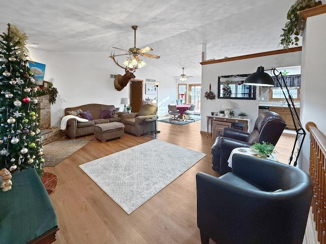 living room featuring a textured ceiling, hardwood / wood-style flooring, vaulted ceiling, and ceiling fan