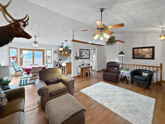 living room featuring ceiling fan, light hardwood / wood-style floors, and vaulted ceiling