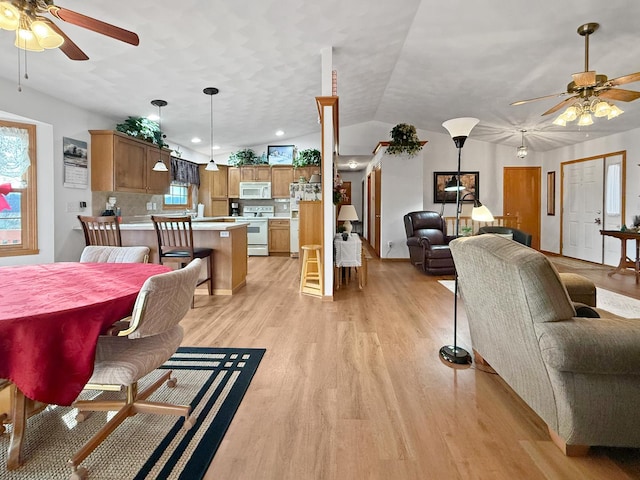 dining space featuring ceiling fan, light hardwood / wood-style floors, a healthy amount of sunlight, and vaulted ceiling