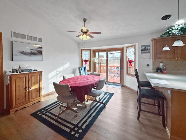 dining space with ceiling fan, light hardwood / wood-style floors, and vaulted ceiling