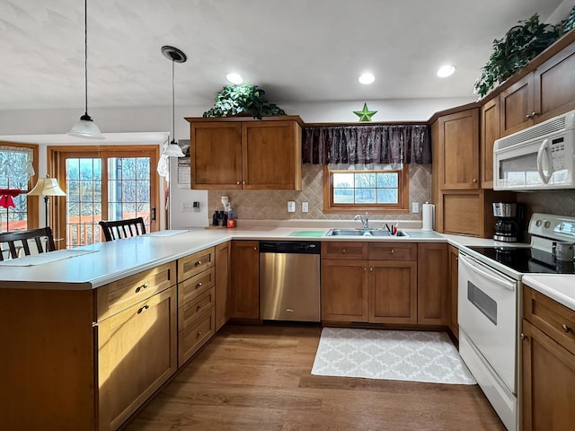 kitchen featuring white appliances, a kitchen breakfast bar, decorative light fixtures, light hardwood / wood-style floors, and kitchen peninsula