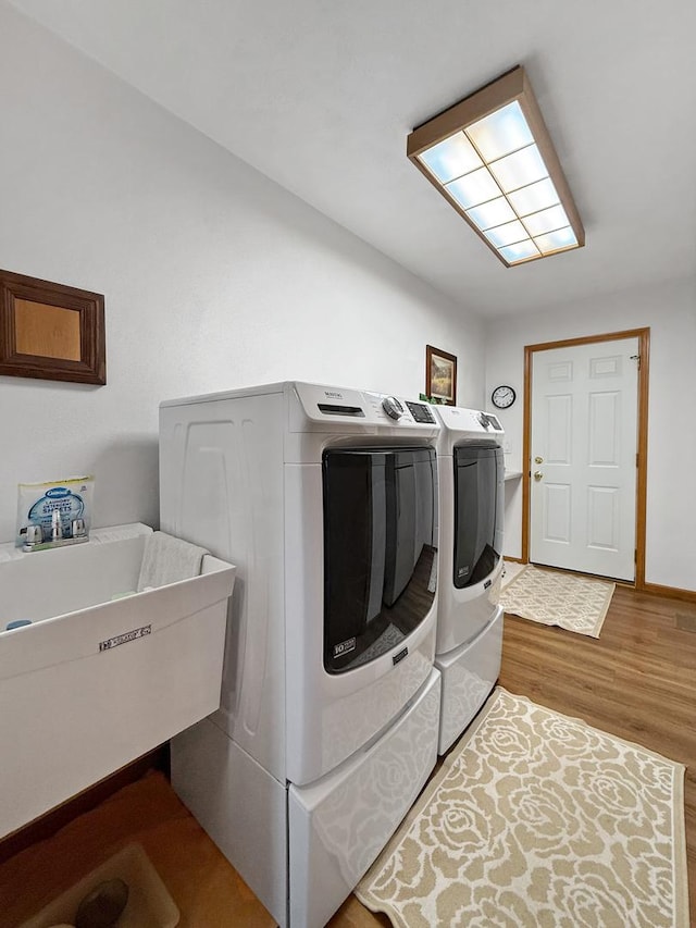 clothes washing area with hardwood / wood-style flooring, independent washer and dryer, and sink