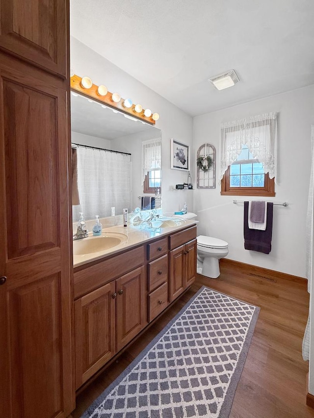 bathroom featuring a wealth of natural light, toilet, vanity, and hardwood / wood-style flooring