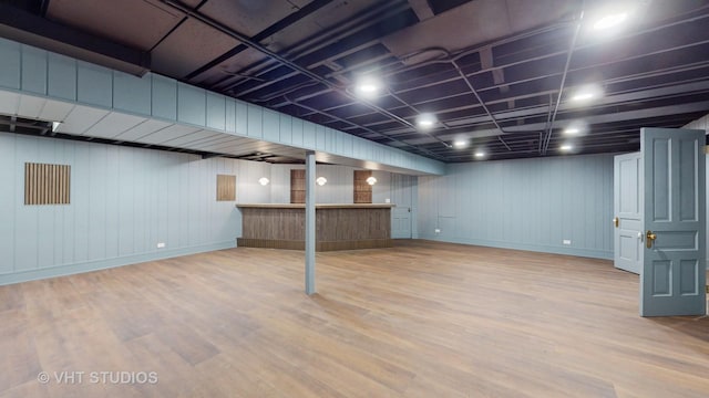 basement featuring wood walls and light wood-type flooring