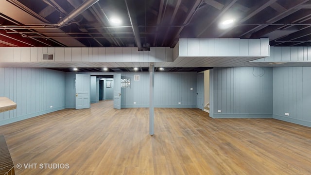 basement with wooden walls and hardwood / wood-style flooring