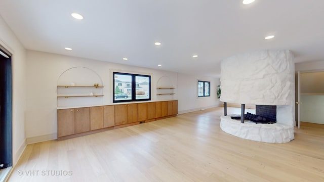 living room with a stone fireplace and light hardwood / wood-style floors