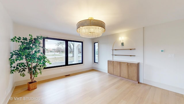 unfurnished living room with light hardwood / wood-style flooring and an inviting chandelier