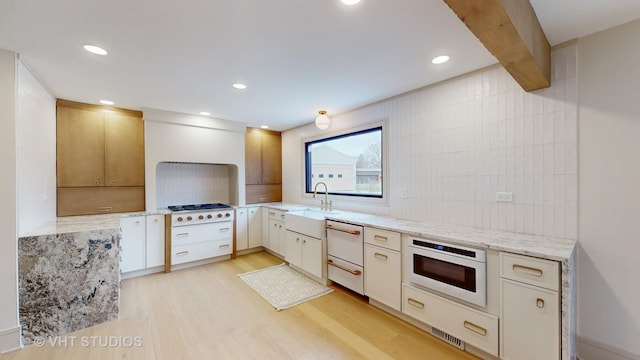 kitchen with backsplash, light stone counters, white appliances, sink, and light hardwood / wood-style flooring