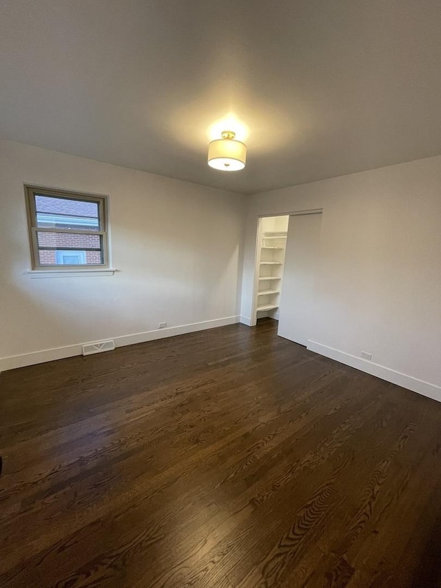 spare room with dark hardwood / wood-style floors and built in features