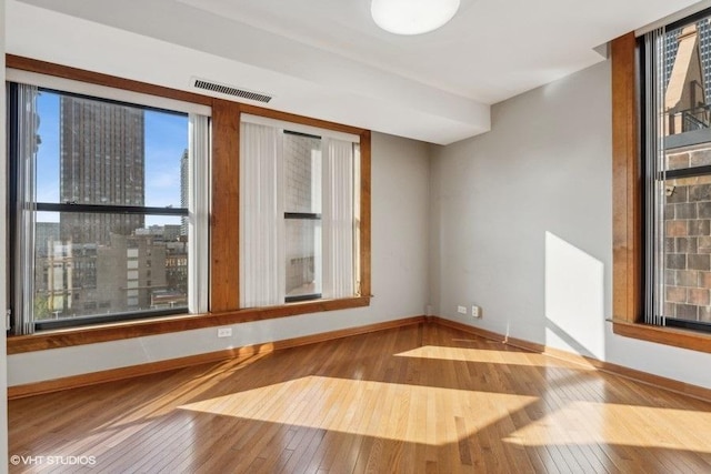 unfurnished room with hardwood / wood-style floors and plenty of natural light