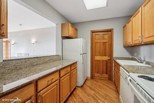 kitchen with light stone counters, white appliances, sink, and light wood-type flooring