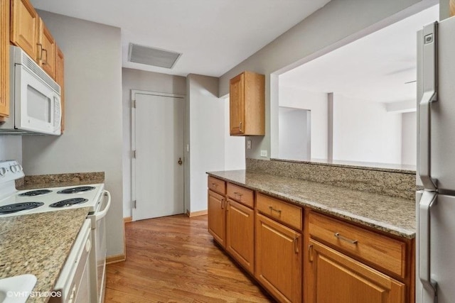 kitchen featuring light stone countertops, white appliances, and light hardwood / wood-style flooring