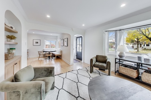 living room with light wood-type flooring, built in features, and ornamental molding