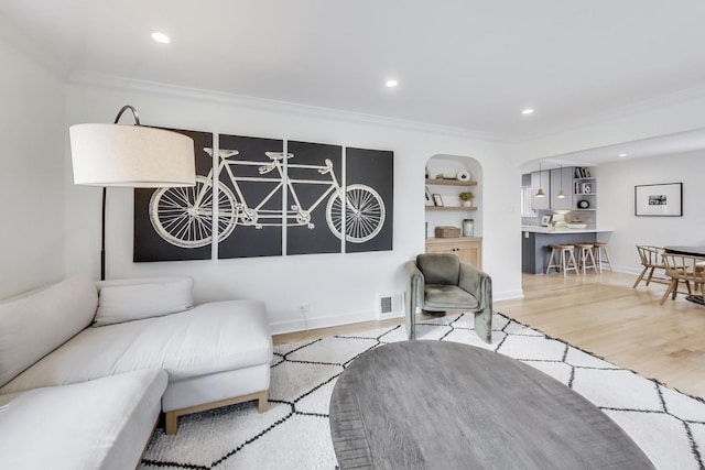 living room with light hardwood / wood-style floors, built in features, and ornamental molding