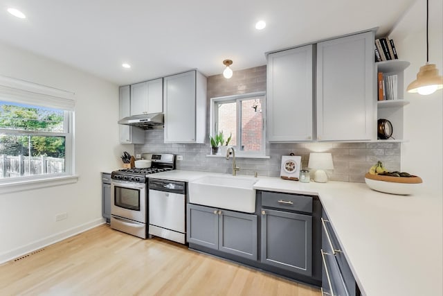 kitchen featuring gray cabinets, stainless steel appliances, backsplash, decorative light fixtures, and sink