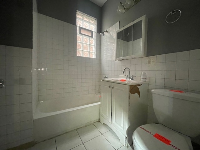 full bathroom with vanity, tiled shower / bath combo, tile walls, tile patterned flooring, and toilet