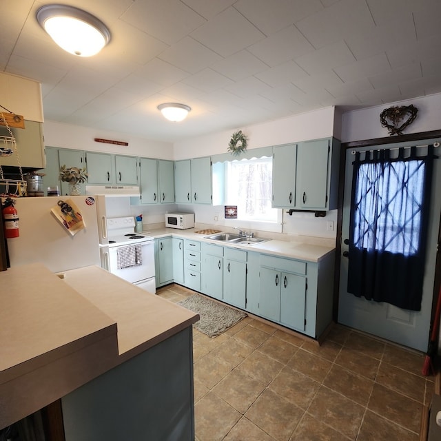 kitchen with dark tile patterned floors, white appliances, and sink