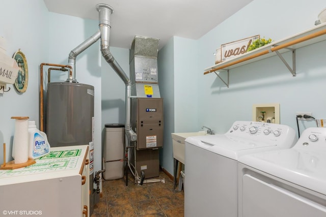 clothes washing area with washer and clothes dryer, sink, and gas water heater