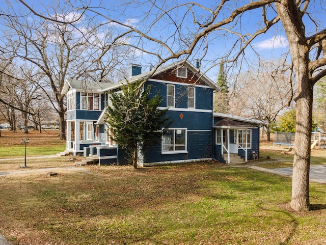 view of front of house with a trampoline, a front lawn, and a sunroom