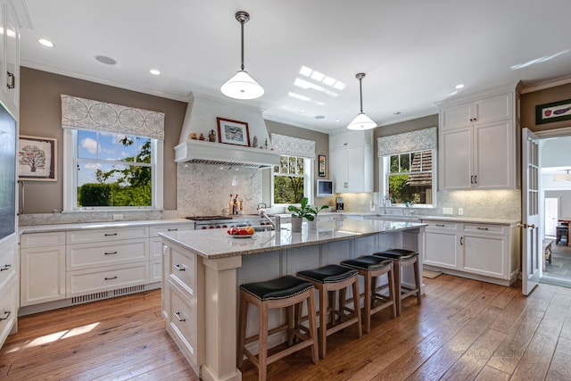 kitchen with backsplash, light hardwood / wood-style floors, and an island with sink