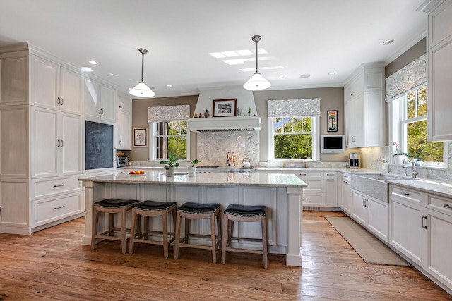 kitchen featuring white cabinets, a kitchen island, and hanging light fixtures