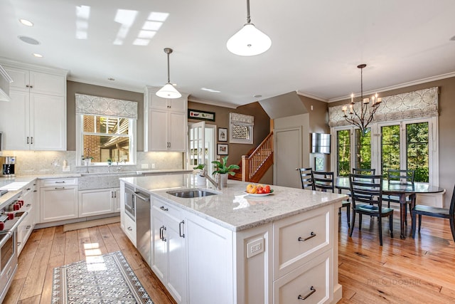 kitchen featuring white cabinetry, sink, an island with sink, and decorative light fixtures